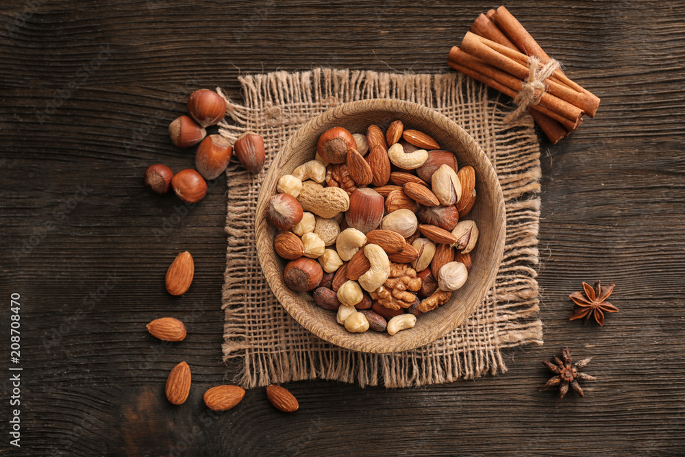 Bowl with various tasty nuts on wooden table