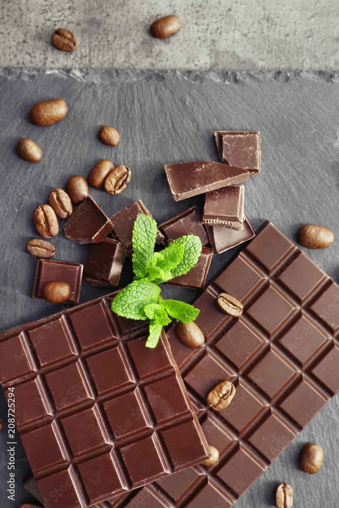 Tasty dark chocolate and coffee beans on table