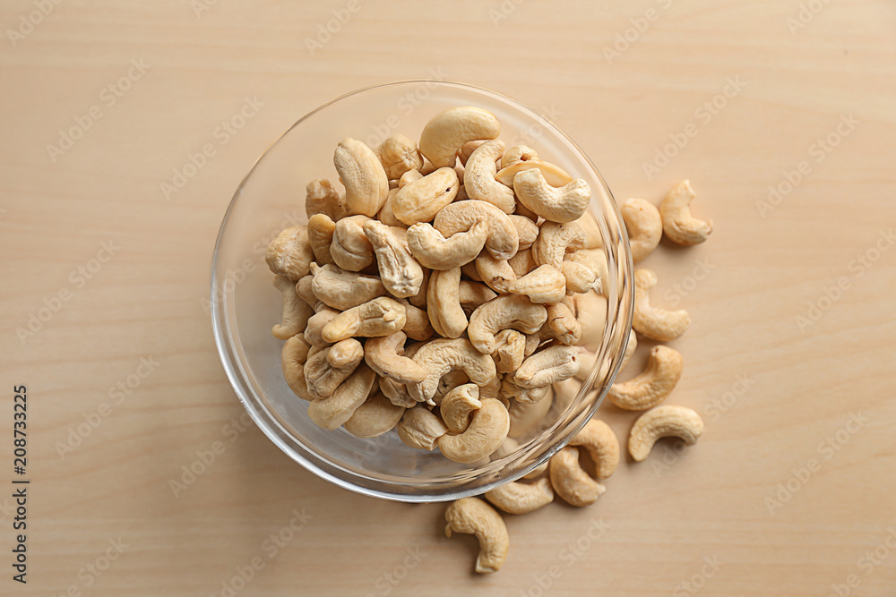 Glass bowl with tasty cashew nuts on wooden table