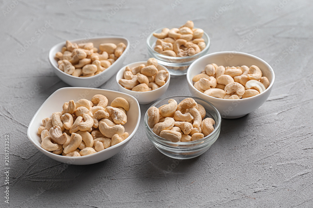 Bowls with tasty cashew nuts on light background