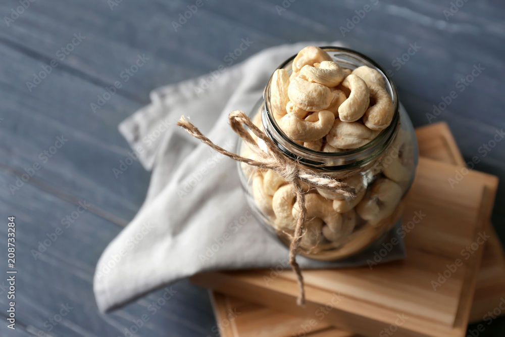 Glass jar with tasty cashew nuts on wooden background