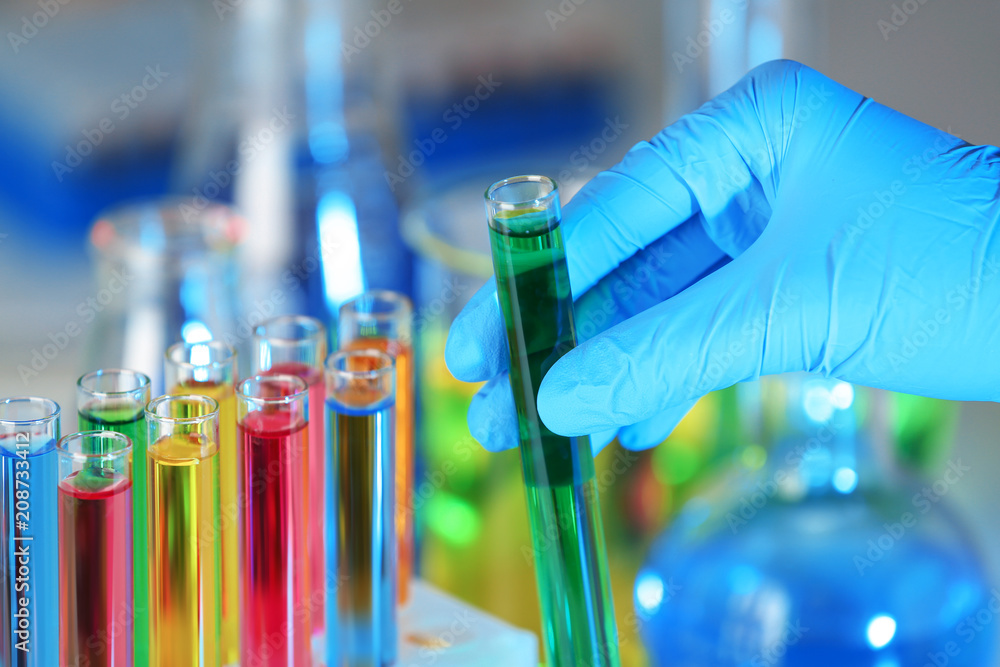 Laboratory worker holding test tube with liquid, closeup