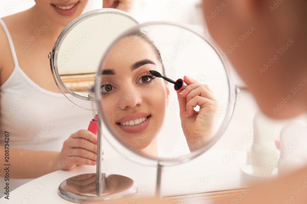 Young beautiful woman applying makeup in morning