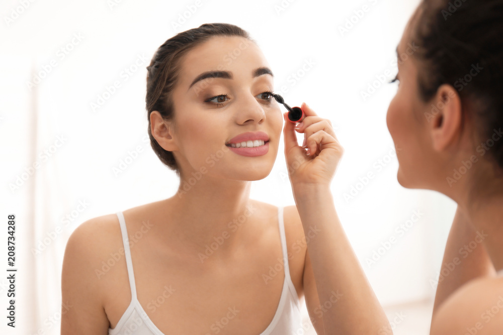 Young beautiful woman applying makeup in morning