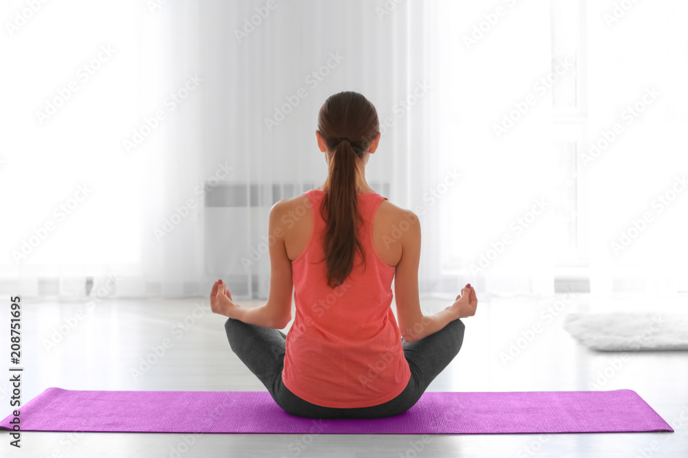 Beautiful young woman practicing yoga in morning