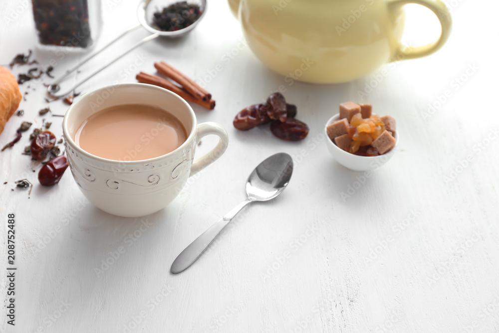 Cup of aromatic tea with milk on wooden table