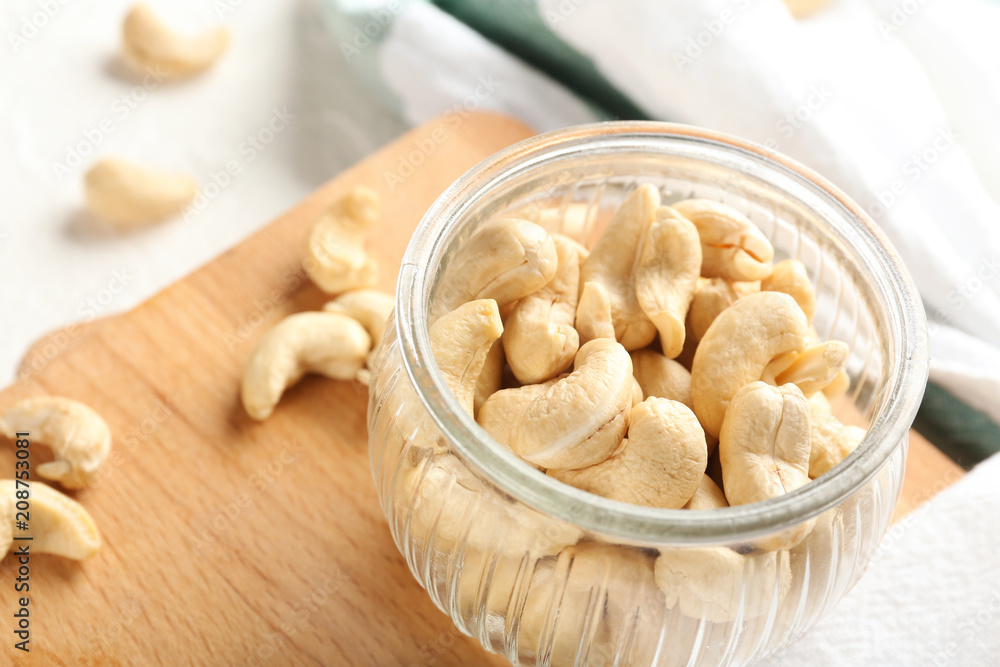 Glass jar with fresh cashew nuts on table, closeup