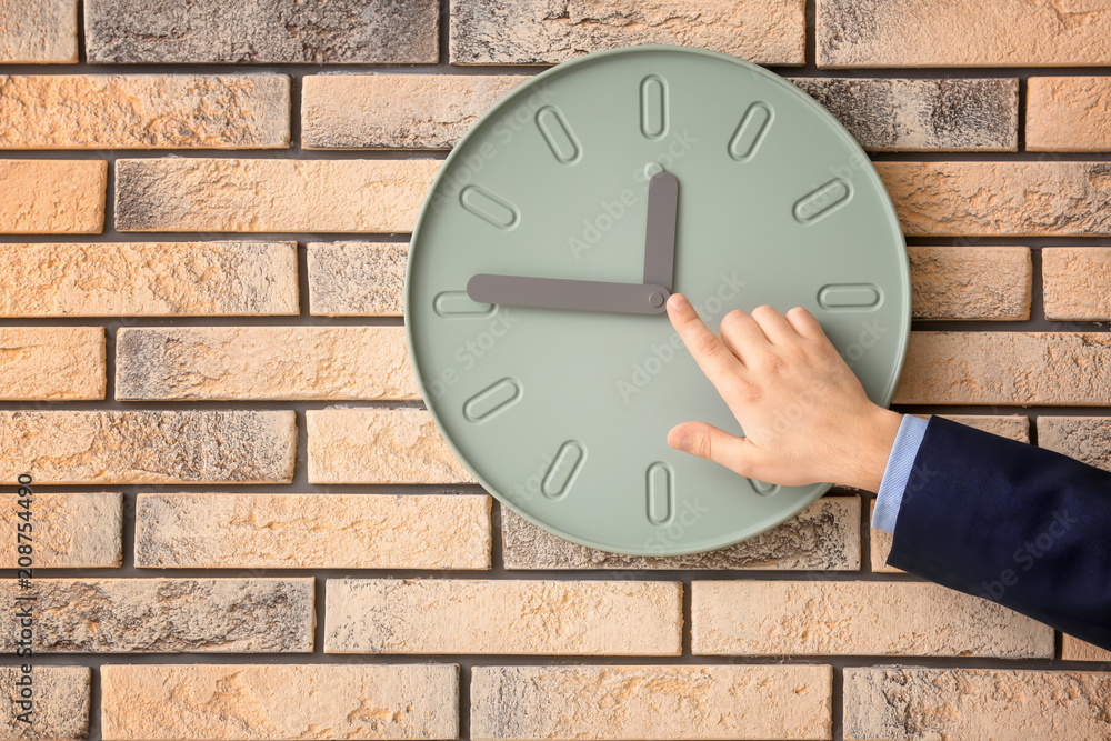 Man pointing on clock against wall background. Time management concept