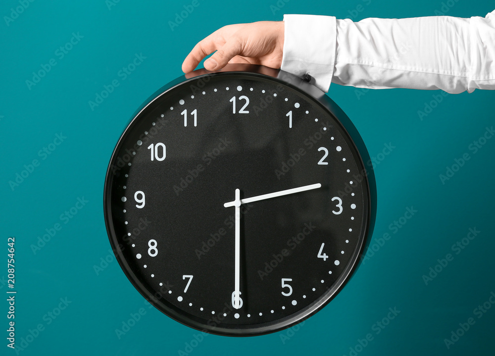 Man holding clock on color background. Time management concept