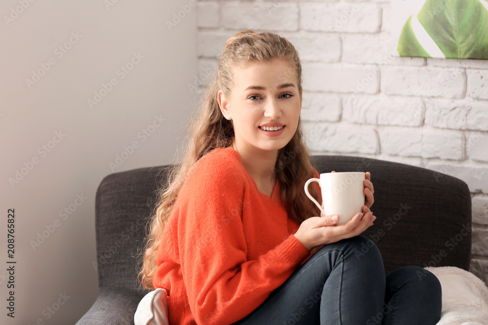 年轻女子在家里的扶手椅上喝茶休息