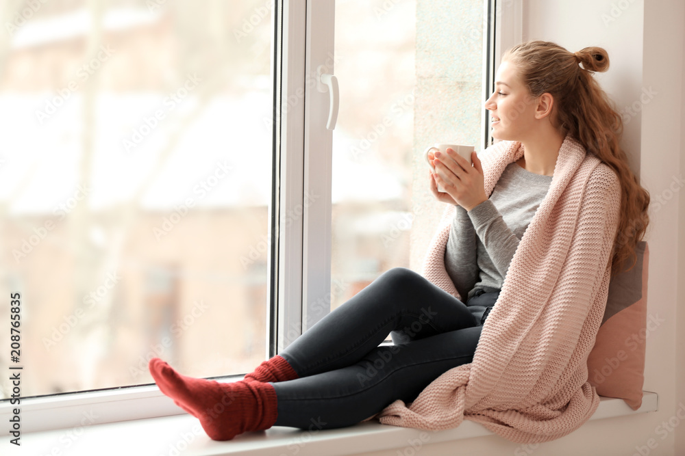 年轻女子在室内靠窗喝茶