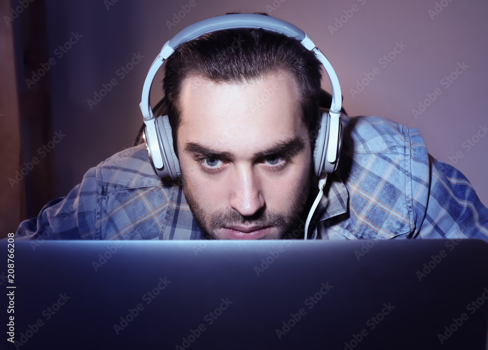 Young man playing video games on laptop at home