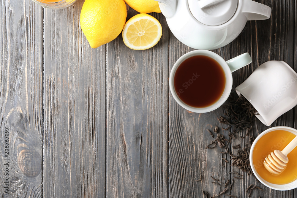 Cup of delicious tea with honey and lemon on wooden table