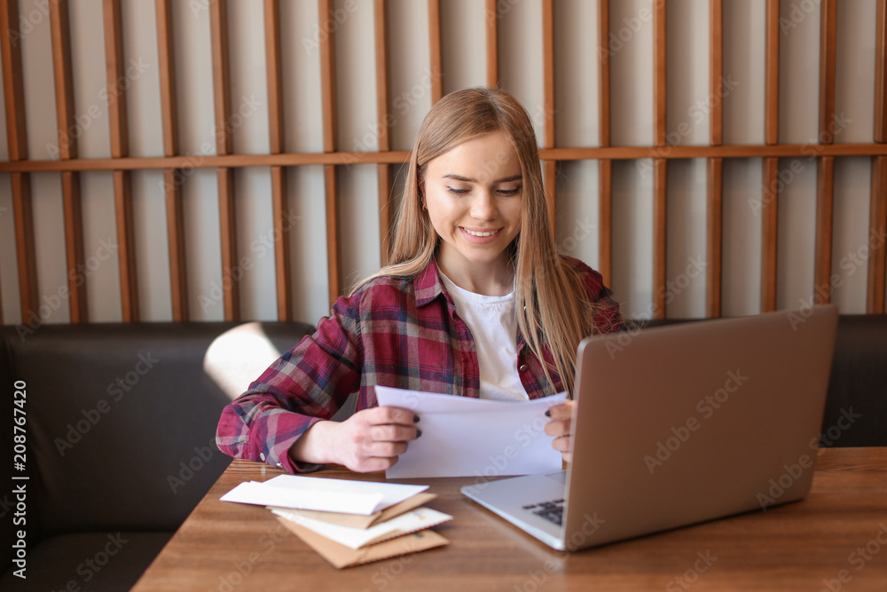 年轻女子在咖啡馆的桌子上读信。邮件递送