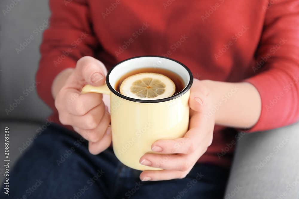 年轻女子拿着一杯柠檬热茶，特写镜头