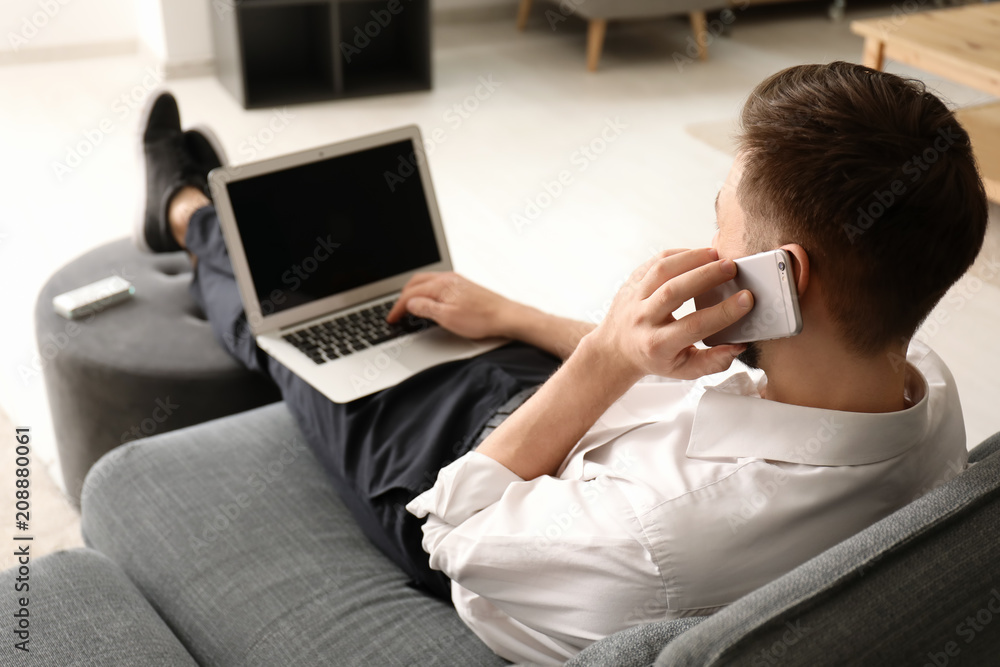 Freelancer talking on phone while using laptop at home