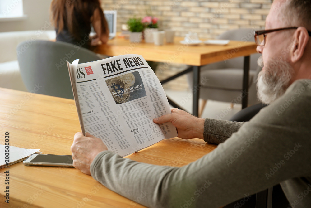 Senior man reading newspaper in cafe