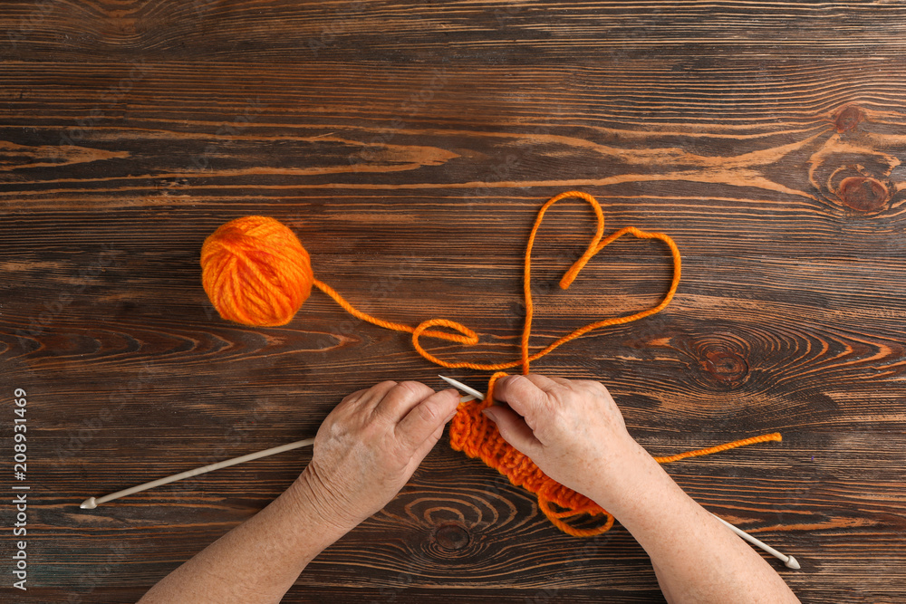 Senior woman knitting sweater at table