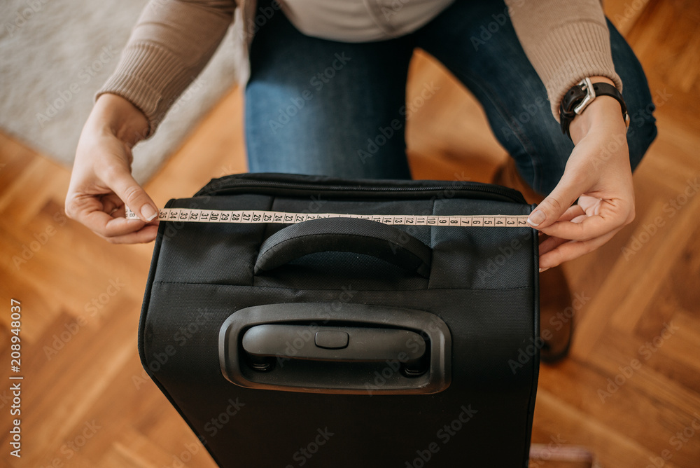 女士在旅行前测量行李。