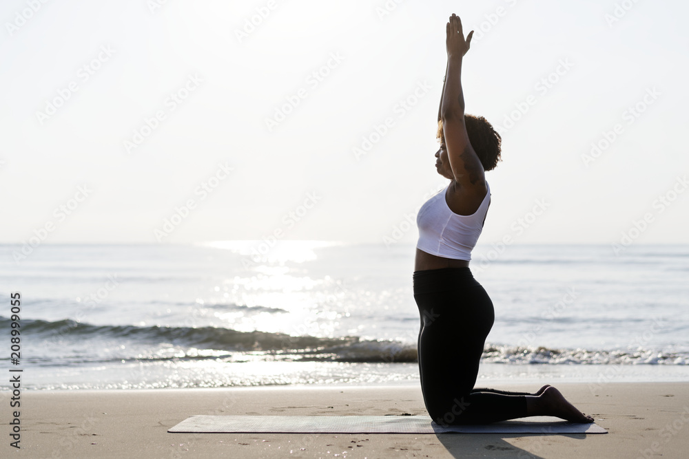 African American woman practicing yoga at the beach