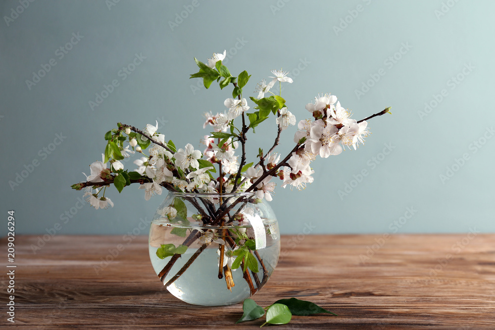 Vase with beautiful blossoming branches on wooden table