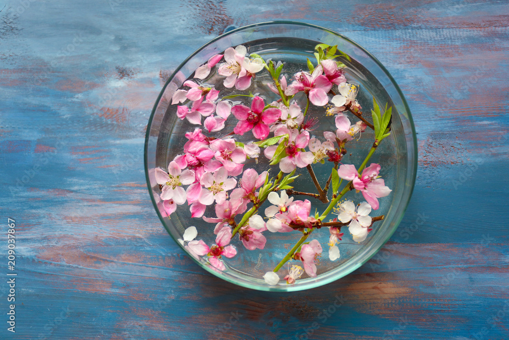 Glass bowl with water and blooming flowers on wooden table