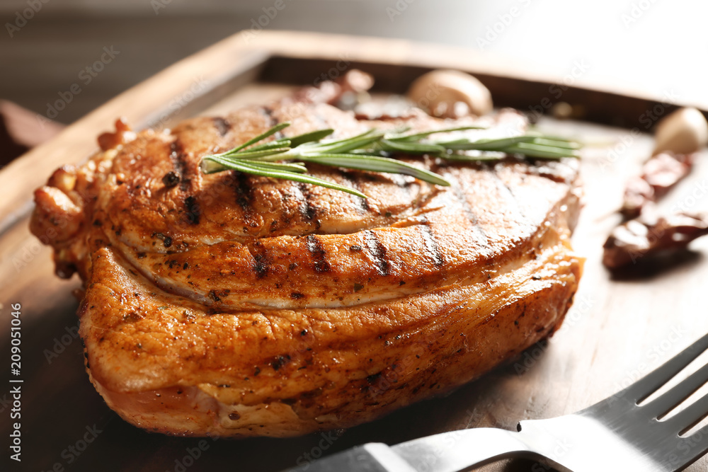 Wooden board with tasty grilled steak and rosemary, closeup