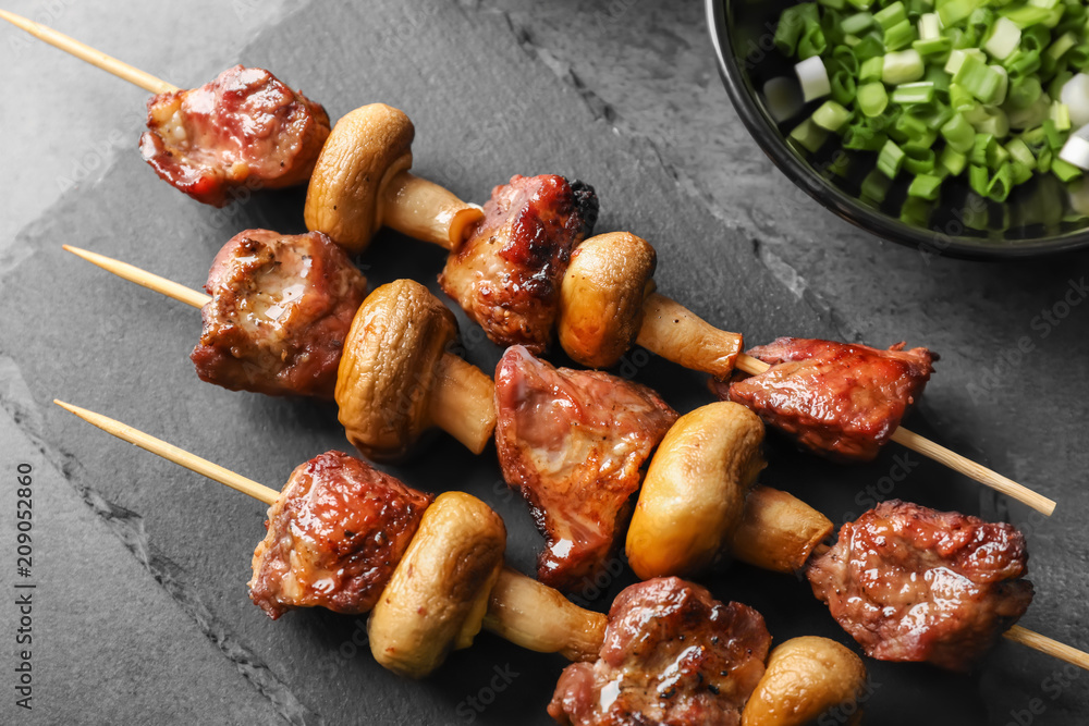 Barbecue skewers with juicy meat and mushrooms on slate plate