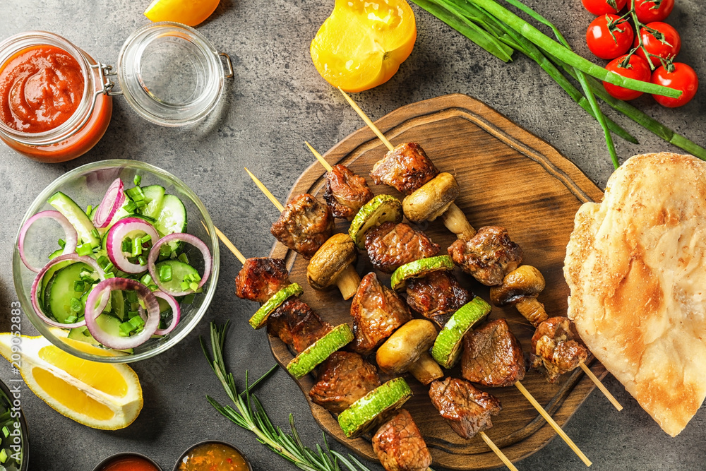 Barbecue skewers with juicy meat and vegetables on wooden board