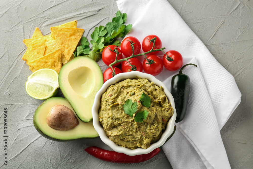 Delicious guacamole with vegetables on textured background