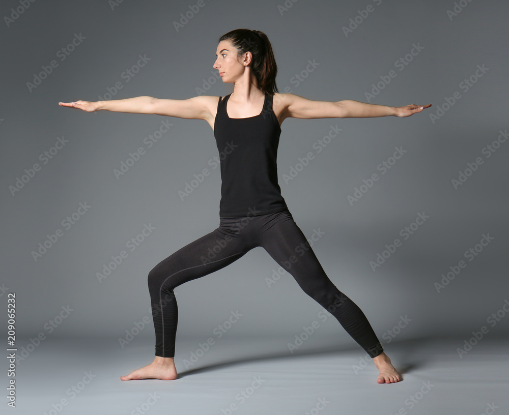 Young woman practicing yoga on grey background