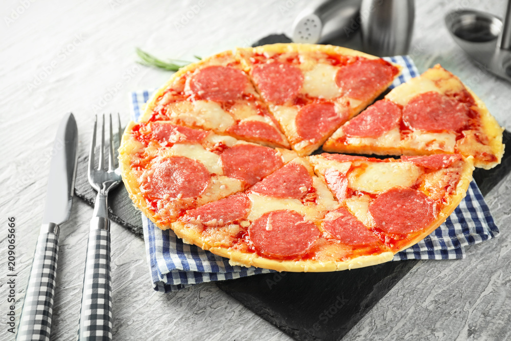 Slate plate with pieces of pepperoni pizza on table