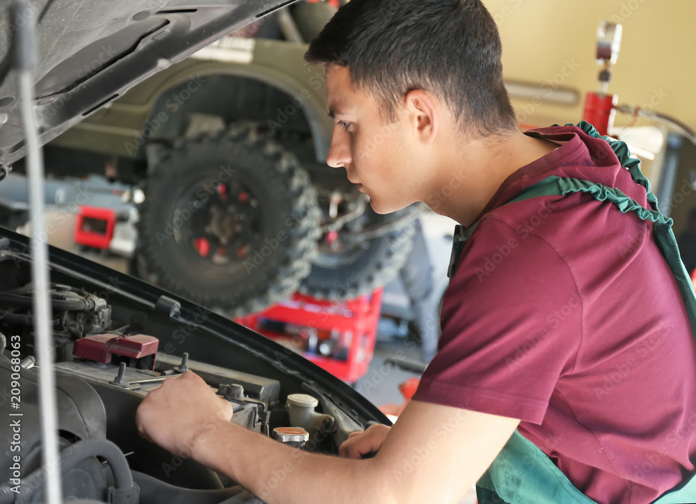 Young auto mechanic repairing car in service center