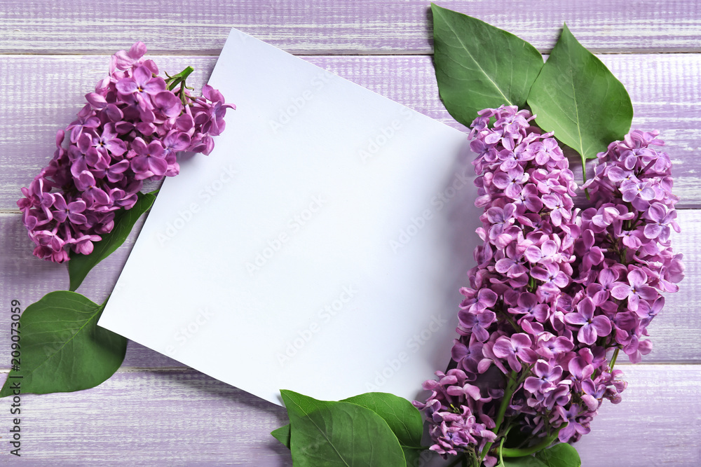 Blank card with lilac flowers on color wooden background