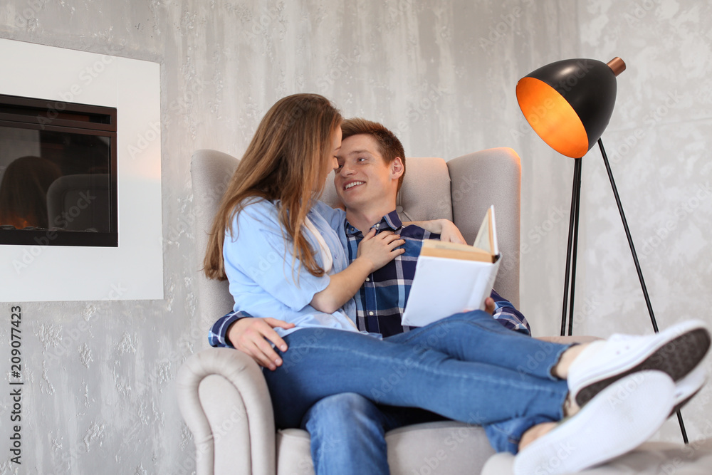 Happy young couple with book resting at home