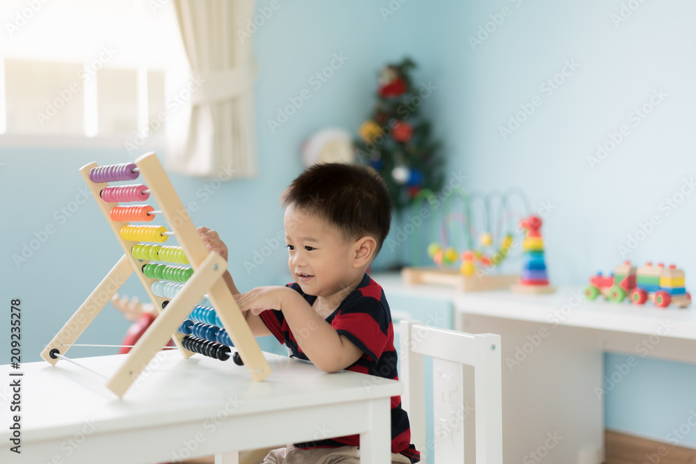 亚洲幼童学会数数。可爱的孩子在玩算盘玩具。小男孩玩得很开心