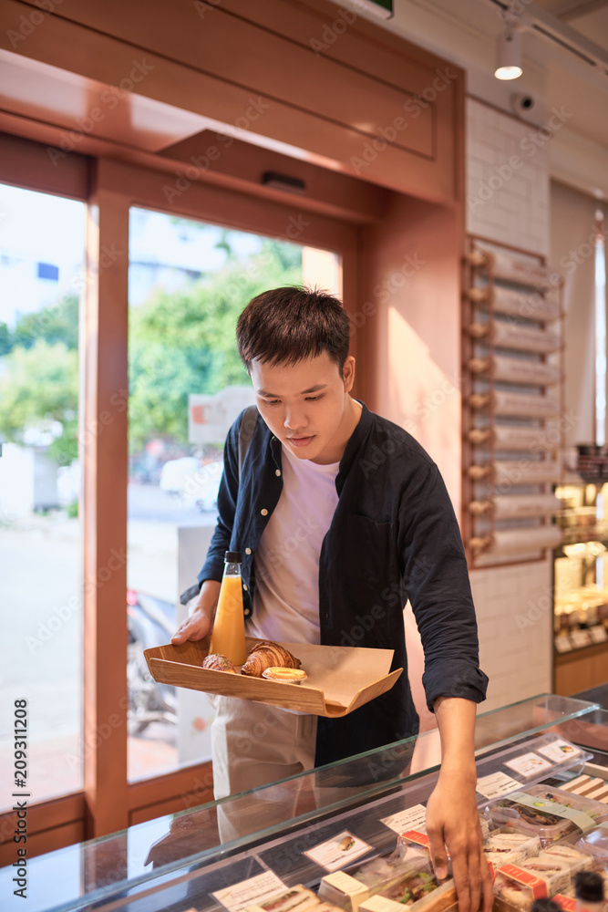 英俊的亚洲男子在下午的咖啡休息时间买面包店。面包店和咖啡休息时间。