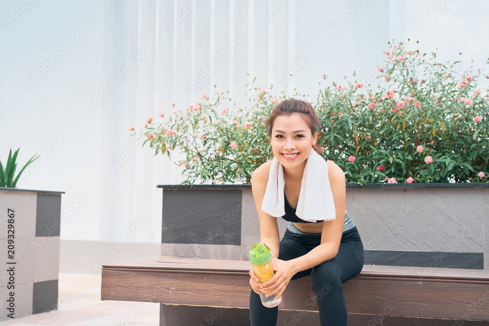 亚洲女子手持水瓶在户外锻炼