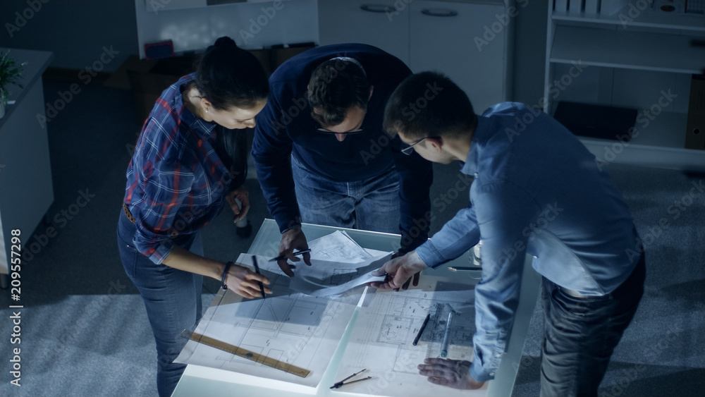 Late at Night Team of Design Engineers Work with Drafts and Documents on Illuminated Table.