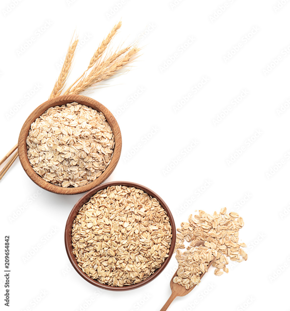 Bowls with raw oatmeal on white background