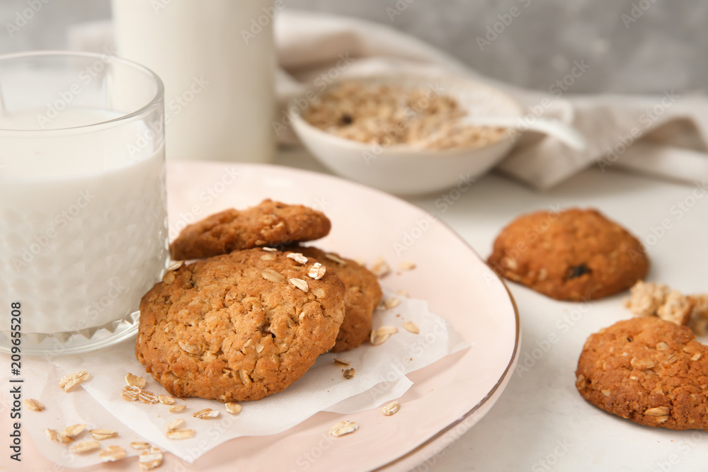 Plate with delicious oatmeal cookies and glass of milk on table, closeup