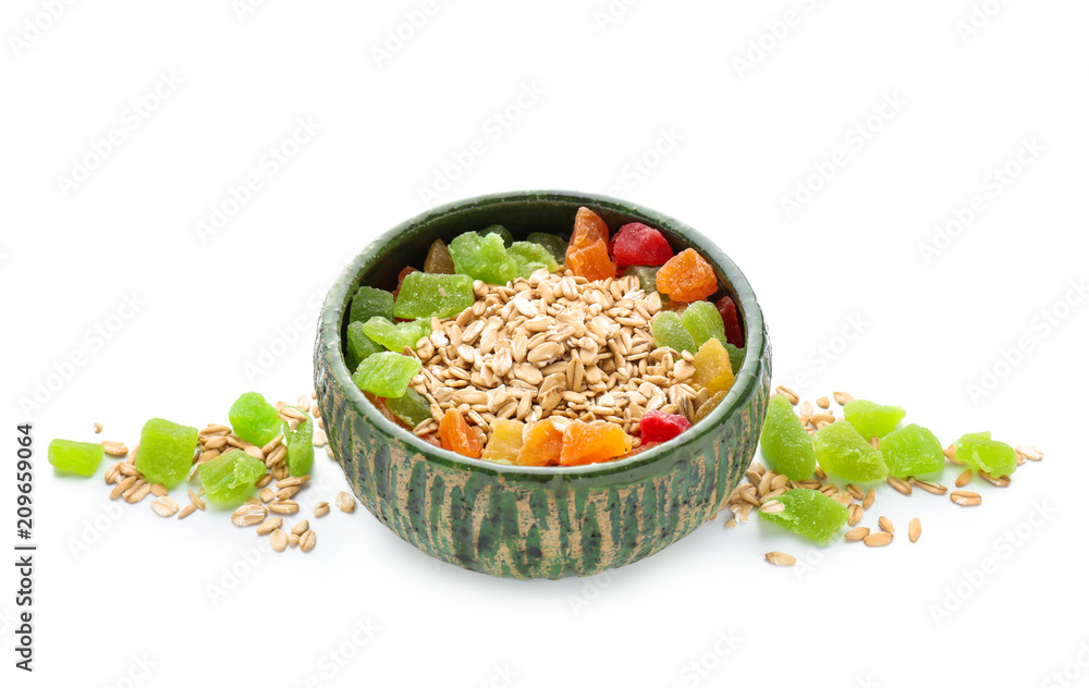 Bowl with oatmeal flakes and candied fruits on white background