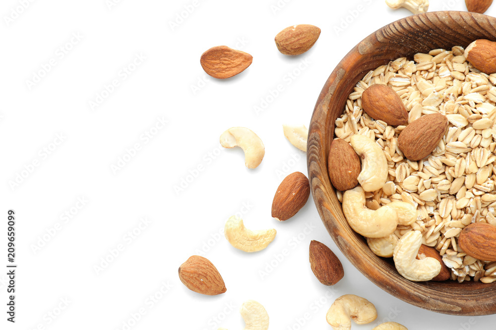 Bowl with raw oatmeal and nuts on white background