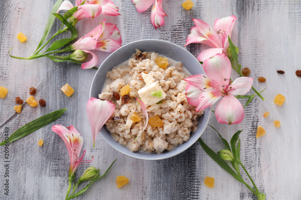 木桌上有美味的燕麦片、蜜糖水果和黄油的碗