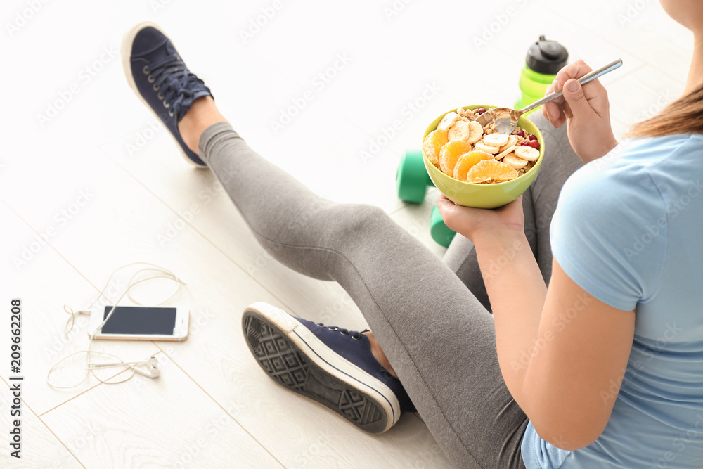 Sporty young woman with bowl of tasty oatmeal at home