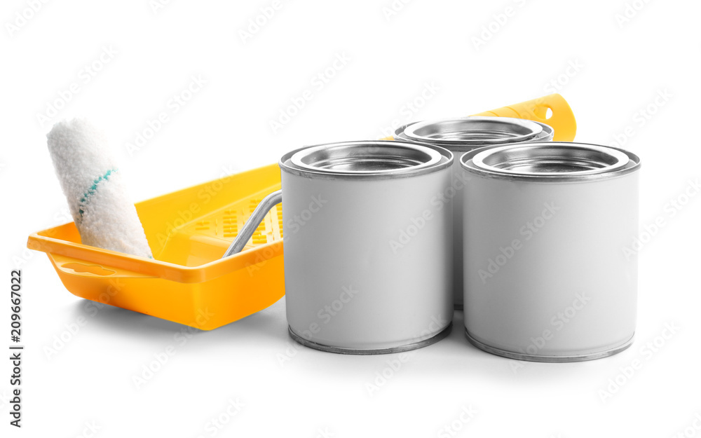 Cans of paint, tray and roller on white background