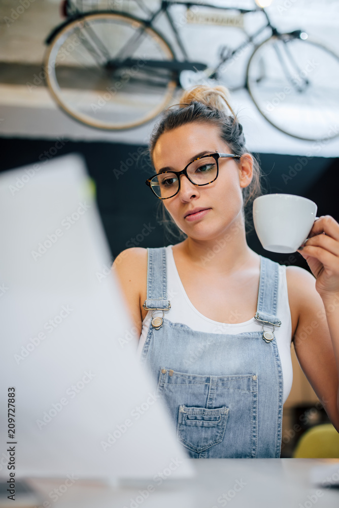 千禧一代时髦女性在室内拿着杯子的特写照片。