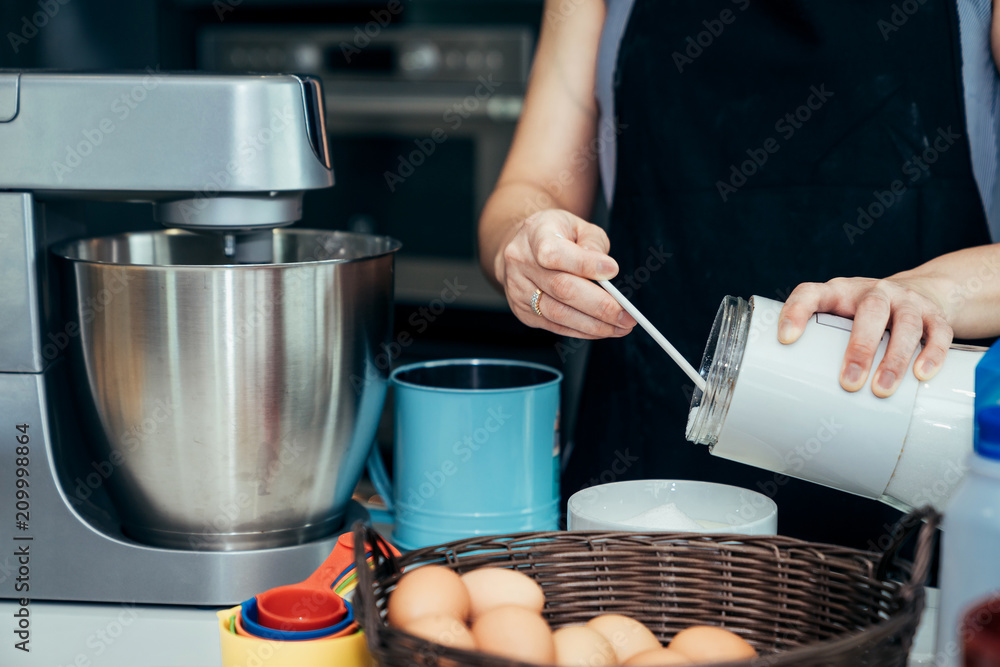 Asian women are mixing the ingredients of a cake in a stainless bowl in her kitchen for weekend part