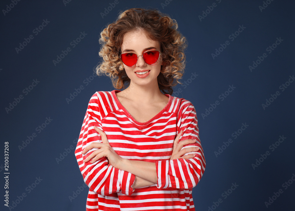 Portrait of beautiful young woman wearing stylish sunglasses on color background