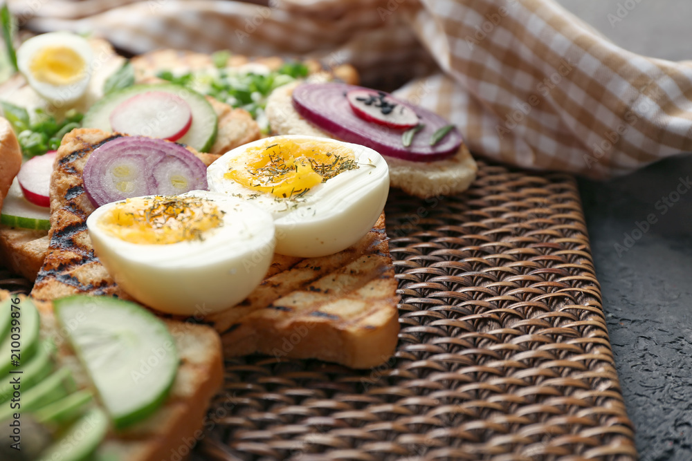 Different delicious toasts on wicker mat, closeup